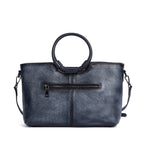 Sac en cuir bleu avec anses rondes, orné d’un médaillon illustrant un cerf stylisé, représentant le modèle Cervus Heritage