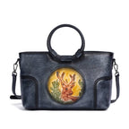 Sac en cuir bleu avec anses rondes, orné d’un médaillon illustrant un cerf stylisé, représentant le modèle Cervus Heritage