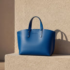 Grand sac à main en cuir véritable bleu royal, avec bandoulière amovible, pochette interne extractible et finitions canon de fusil brillantes, format 48 × 31 × 11 cm. 